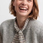 Kvinde iført brun ternet bluse med sløjfe