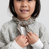 Pige iført hvid pointelle bluse, grå cardigan og ternet tørklæde