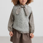 Børn iført kaki nederdel og strikvest set forfra