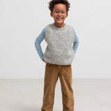 Dreng iført blå og hvid stribet bluse med grå strikvest og brune bukser