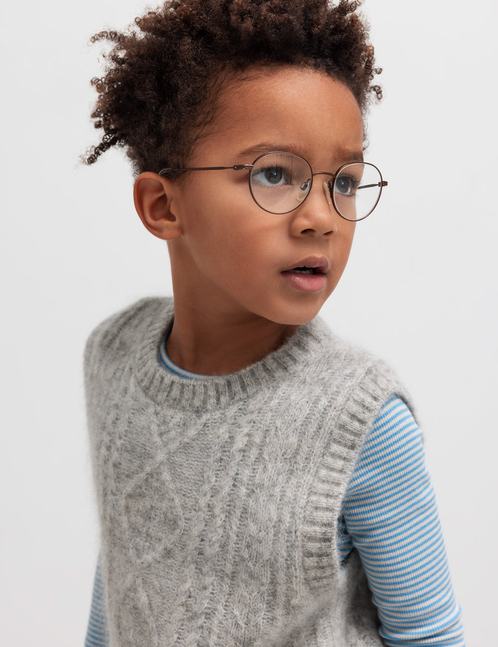 Dreng iført blå og hvid stribet bluse under grå strikvest.