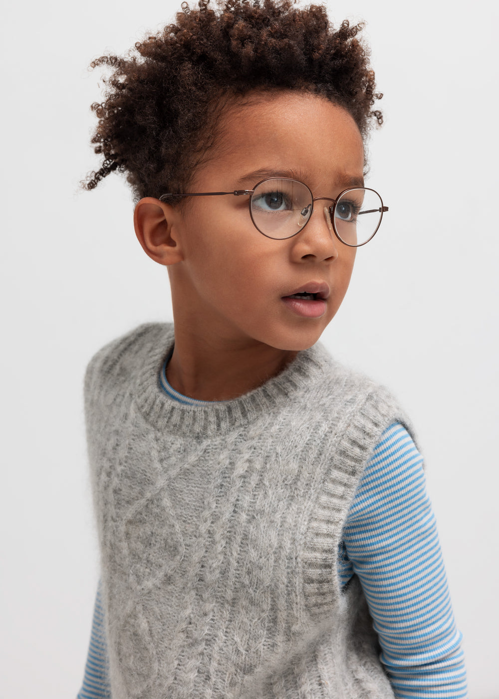 Dreng iført blå og hvid stribet bluse under grå strikvest