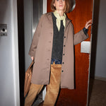 Kvinde iført kaki chino frakke, der åbner dør