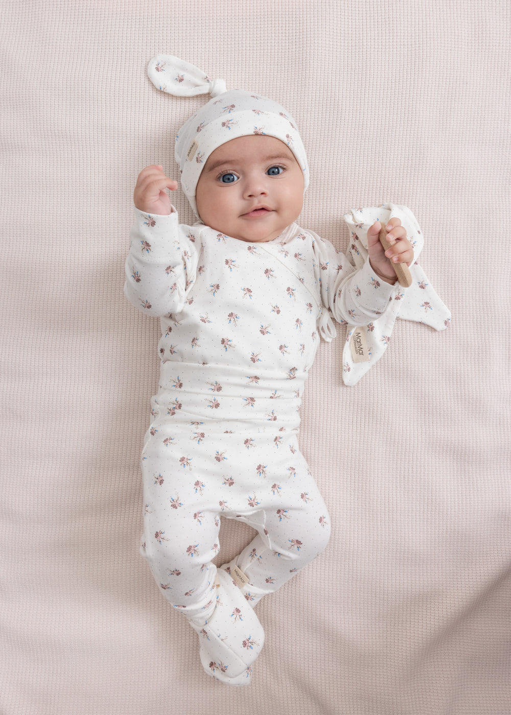 Baby iført blødt babytøj og futter liggende på ryggen