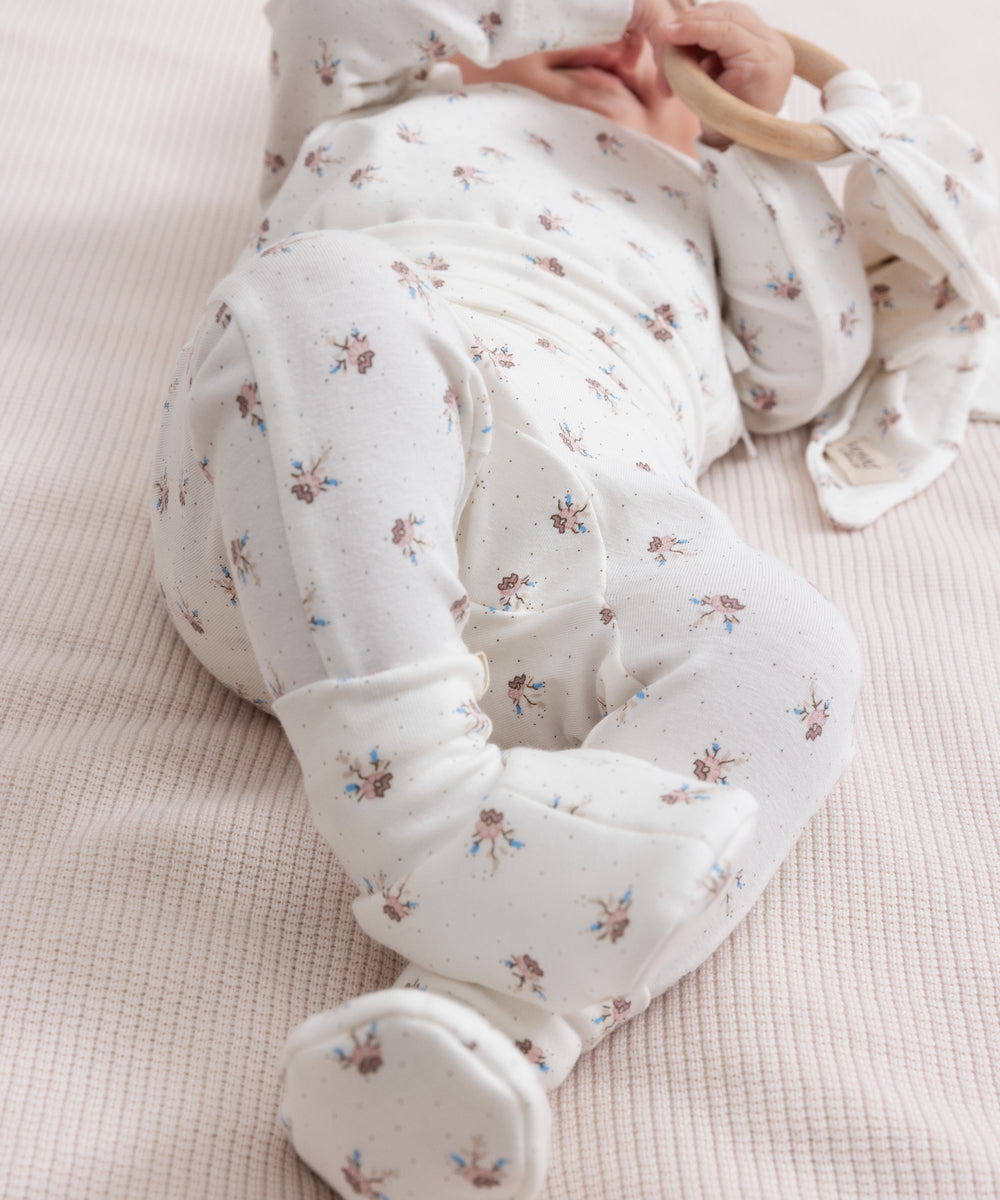 Baby iført blødt babytøj og futter liggende på ryggen