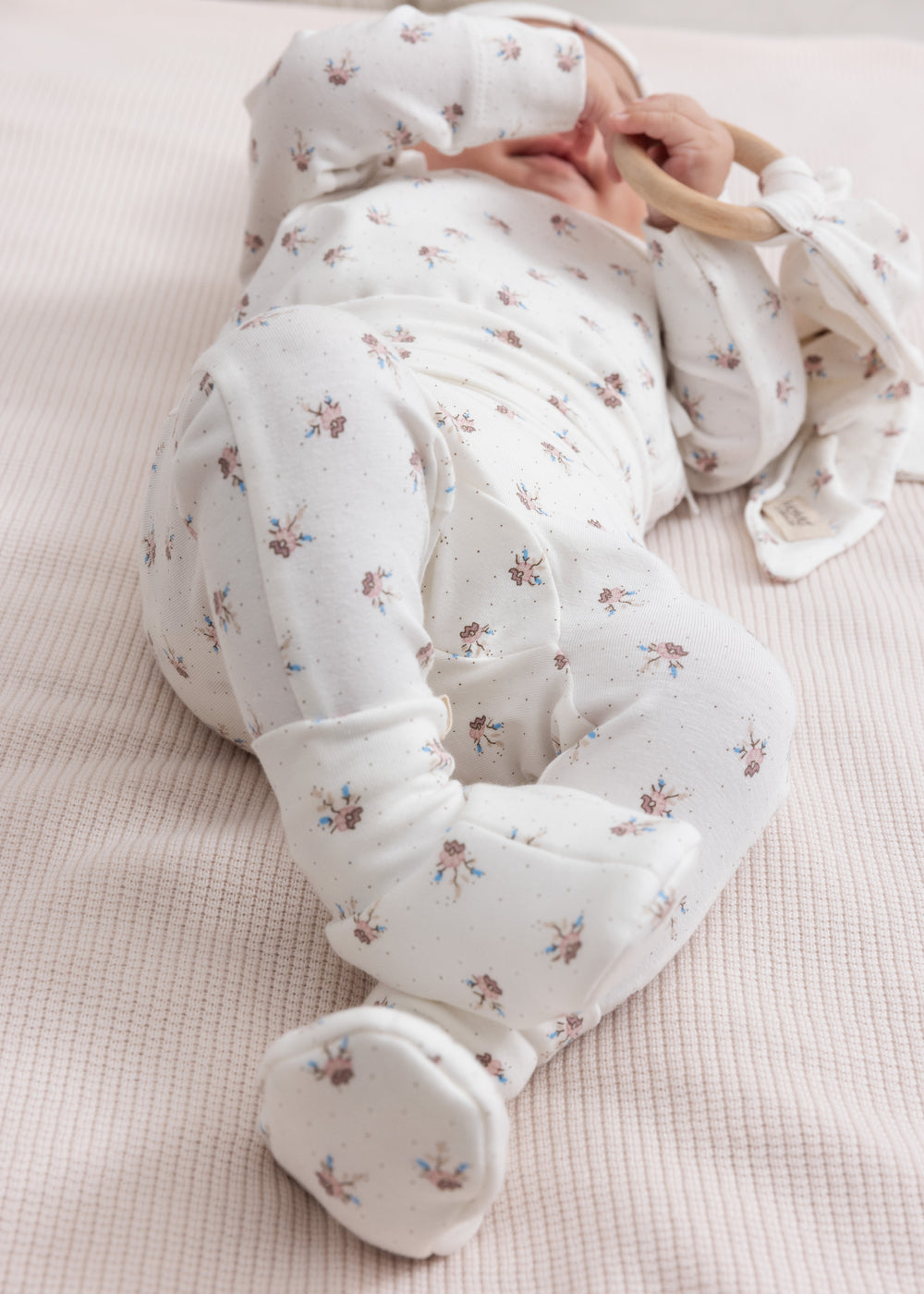 Baby iført blødt babytøj og futter liggende på ryggen