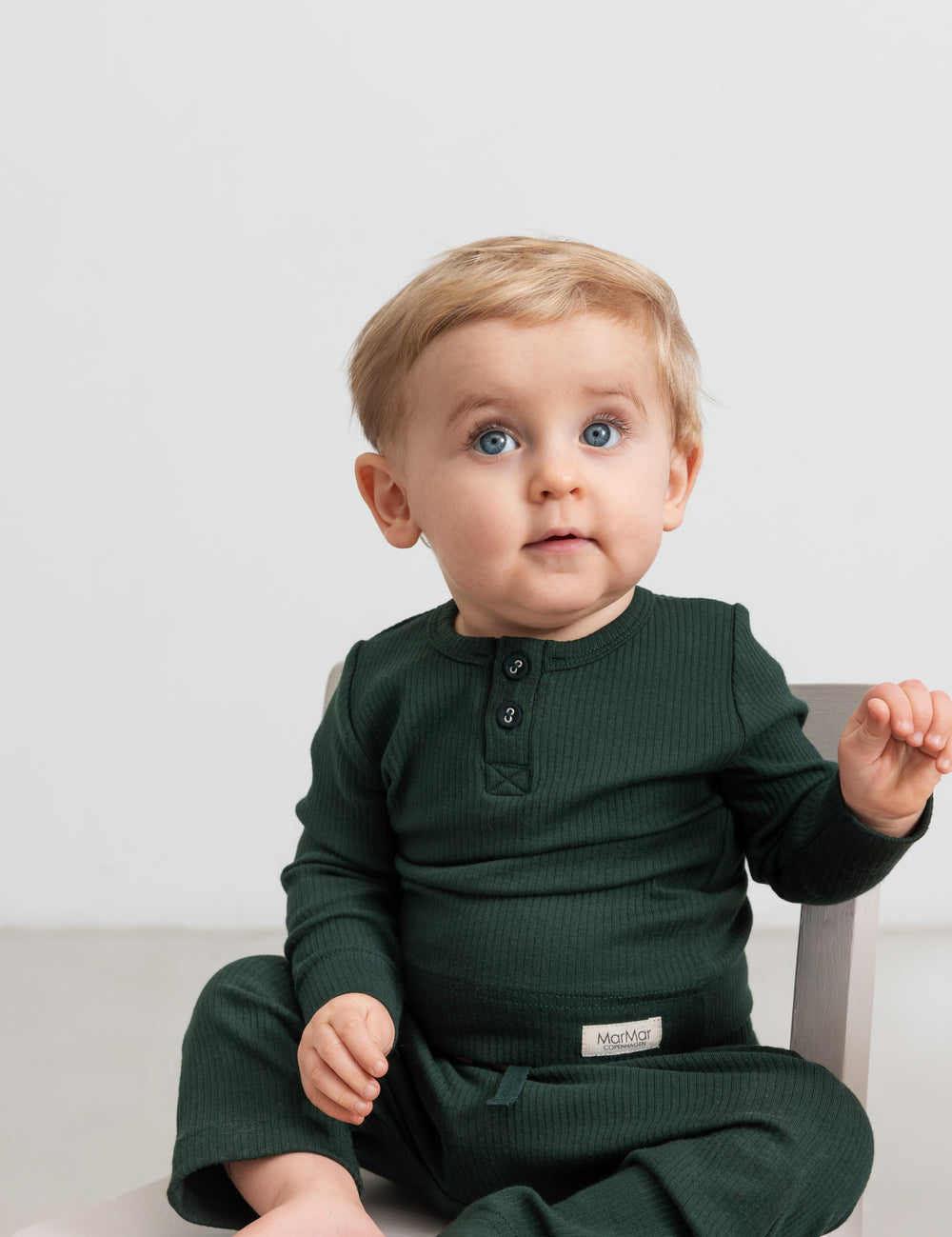 Baby iført mørkegrøn ribbet body med stolpeknapper