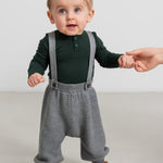 Baby iført grå strikkede selerbukser og mørkegrøn bluse