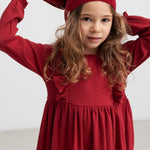 Pige i rød ribstrikket julekjole med flæser på skuldrene og nissehue