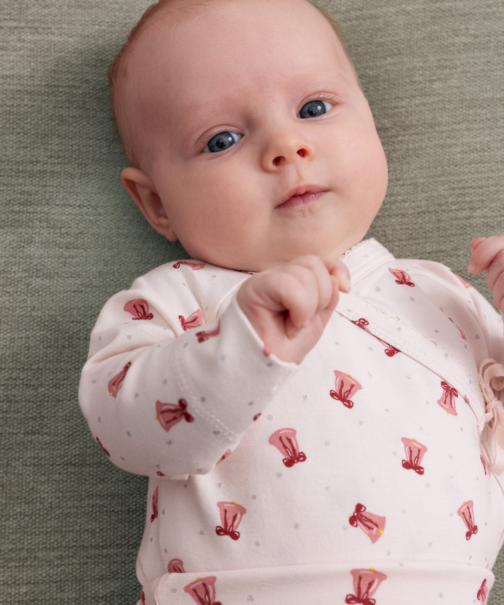 Baby iført cremefarvet slå-om bluse med rødt juleklokkeprint