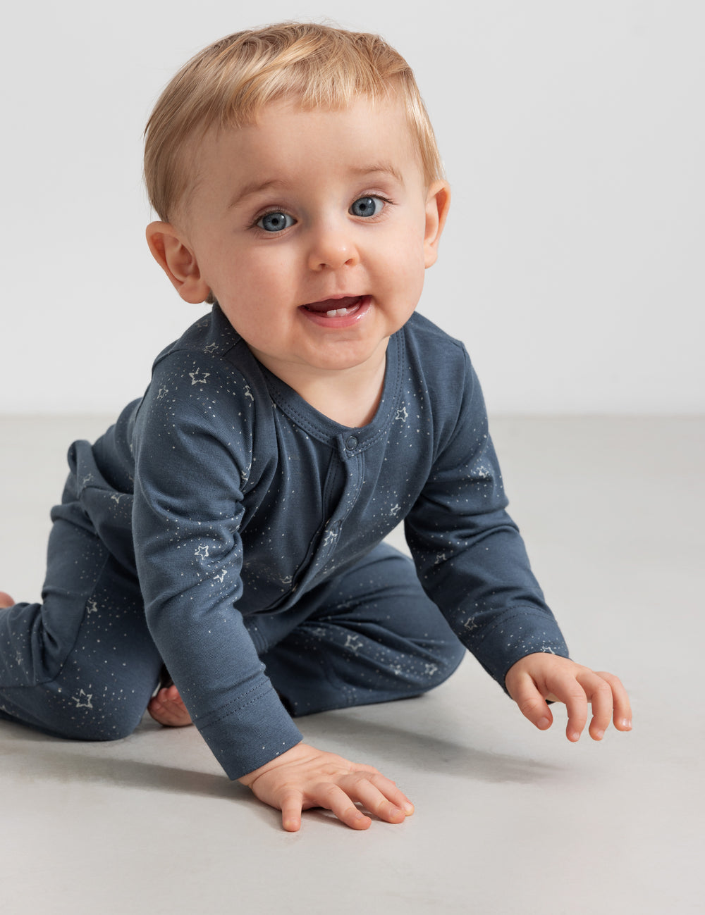 Baby iført mørkeblå heldragt med stjerneprint