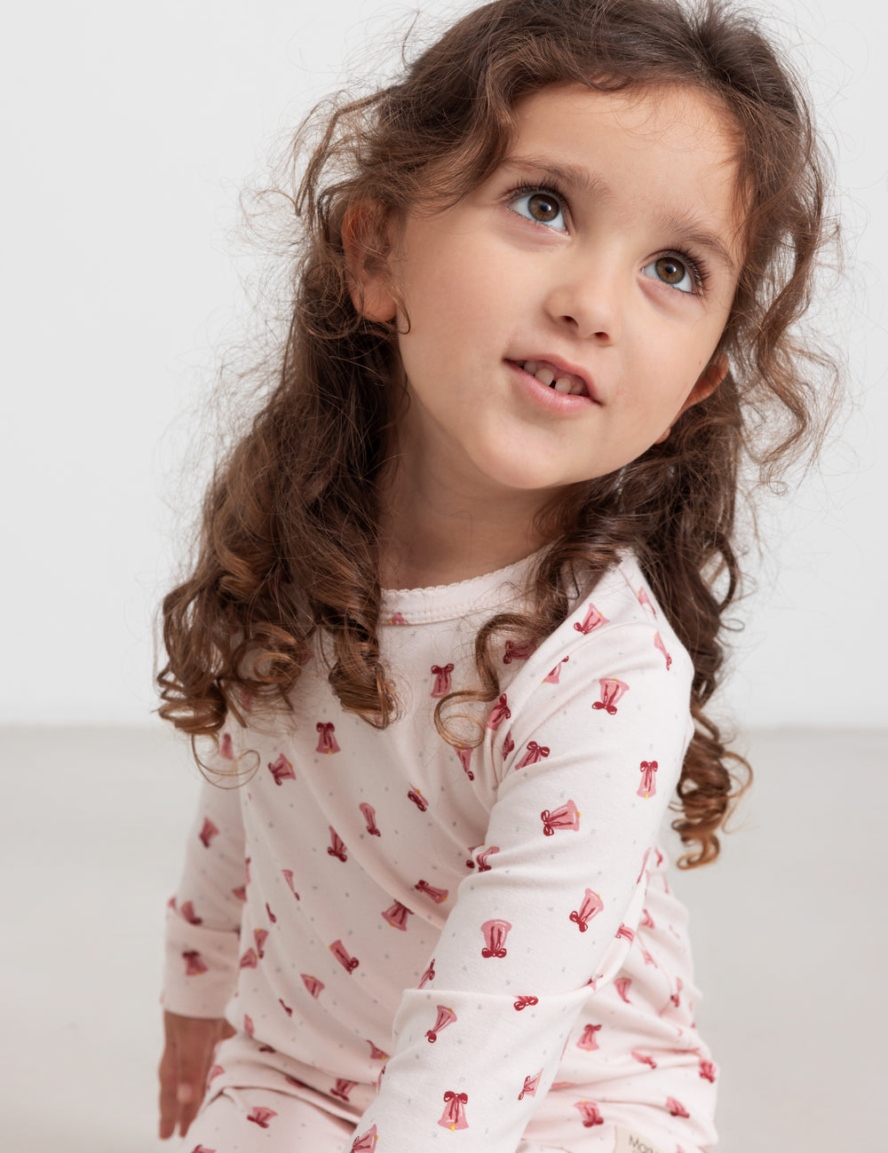 Børn iført cremefarvet julepyjamas med røde juleklokker