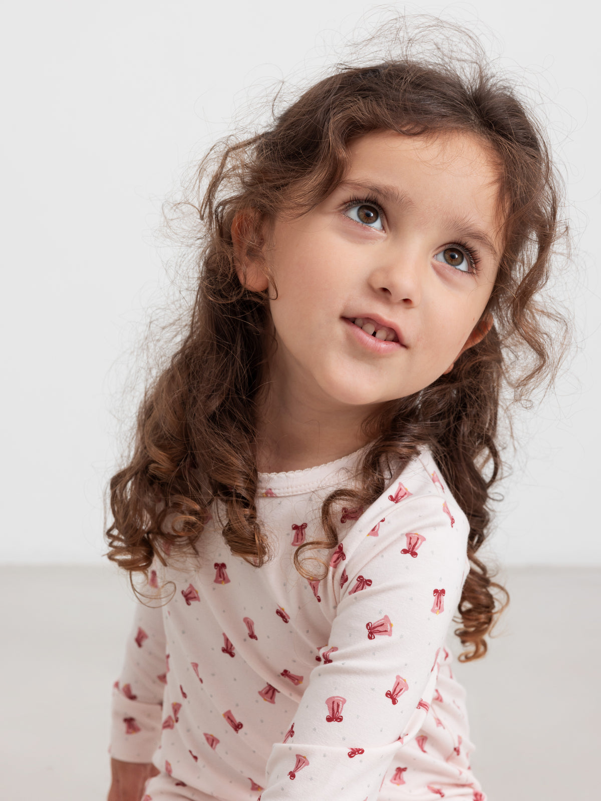 Barn i lyserød trøje med håndtegnet print af små juleklokker