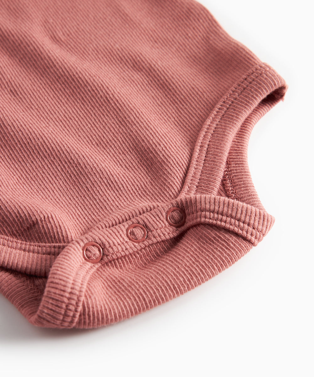 Støvet rosa ribstrikket body med lange ærmer til baby