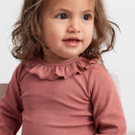 Baby iført støvet rosa body med flæsekrave