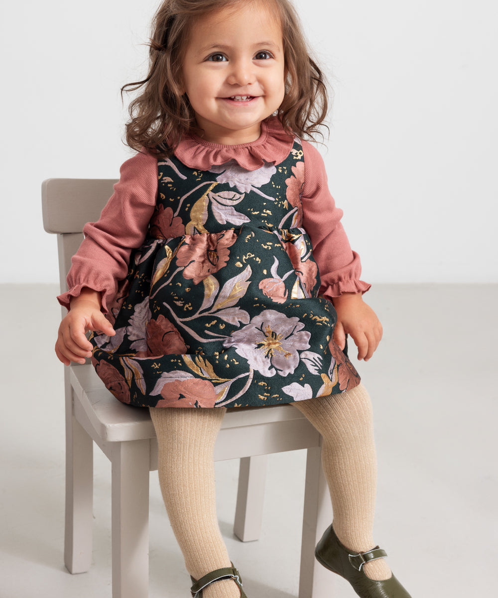 Baby iført støvet rosa body og blomsterprintet kjole