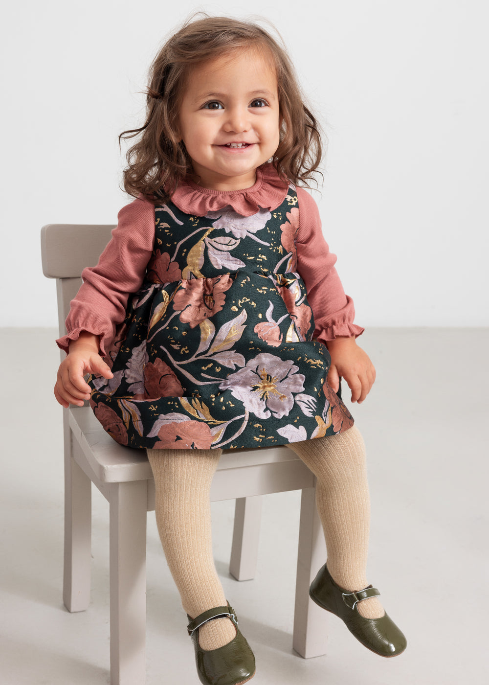 Baby iført støvet rosa body og blomsterprintet kjole