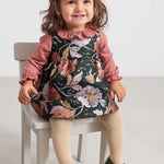 Baby iført mørkegrøn ærmeløs festkjole med blomsterprint og rosa bluse