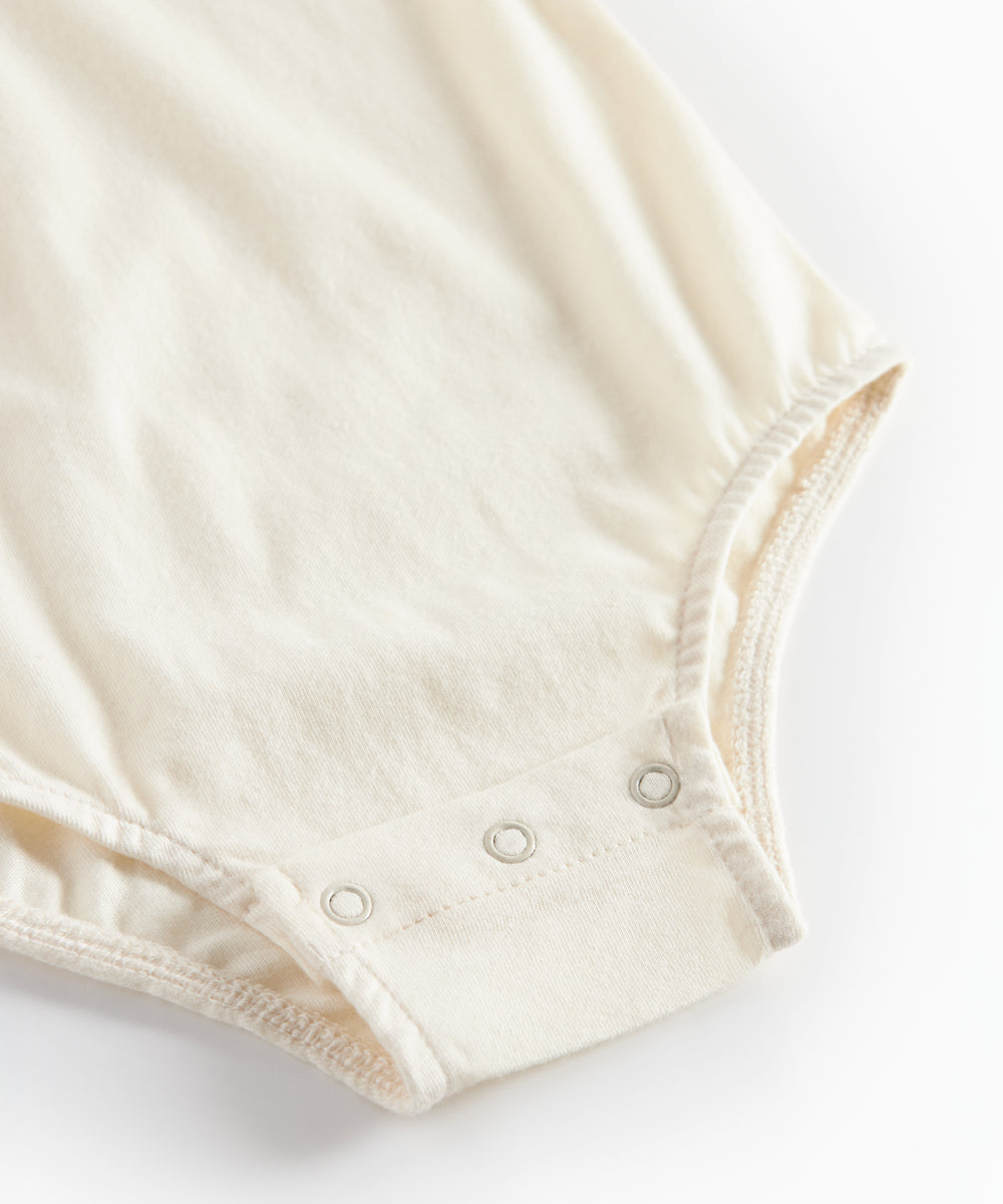 Hvid bodystocking med krave og fine blomsterbroderier til baby