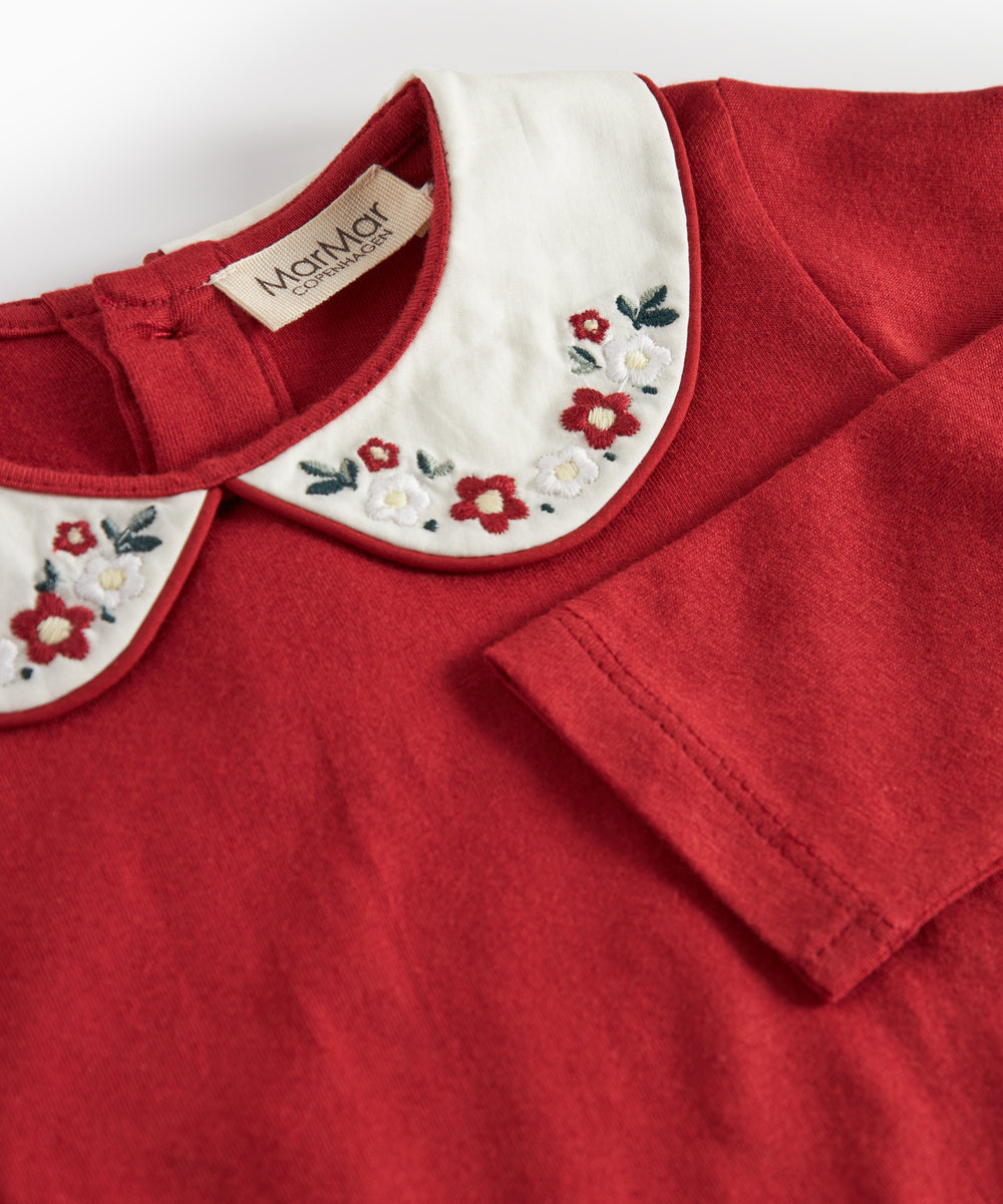 Julerød baby bodystocking med hvid krave og fine blomsterbroderier