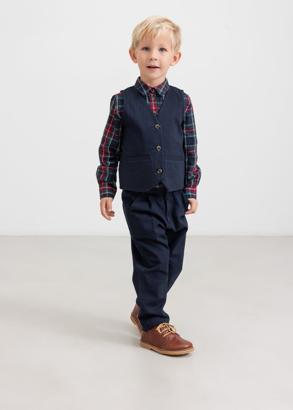 Dreng iført mørkeblå bukser og ternet skjorte i julelook til børn