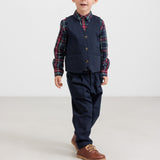 Dreng iført mørkeblå festbukser og vest med ternet skjorte i julelook til børn