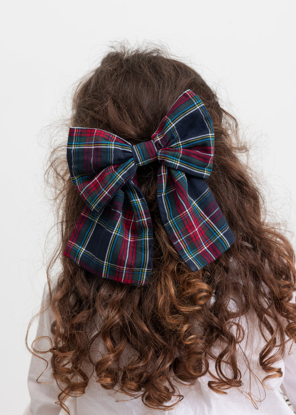 Pige med stort ternet sløjfspænde i håret i juleinspirerede mørkeblå, grøne og røde nuancer