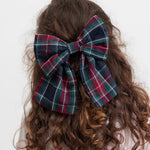 Pige med stort ternet sløjfspænde i håret i juleinspirerede mørkeblå, grøne og røde nuancer