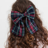 Pige med stort ternet sløjfspænde i håret i juleinspirerede mørkeblå, grøne og røde nuancer