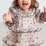 Baby iført lyserød julekjole i tyl med sorte prikker og flæser