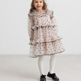 Pige iført lyserød julekjole med dots og cremefarvede strømpebukser til børn