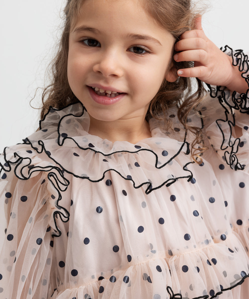 Pige iført lys beige julekjole i tyl med sorte prikker