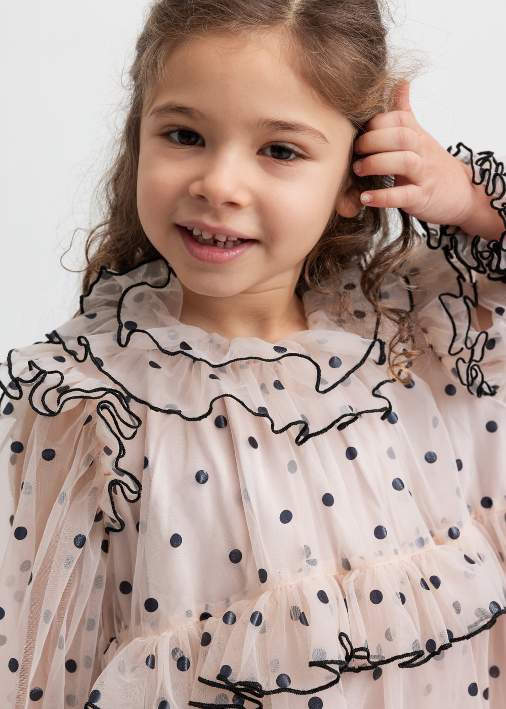 Pige iført lys beige julekjole i tyl med sorte prikker