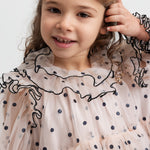 Pige iført lys beige julekjole i tyl med sorte prikker