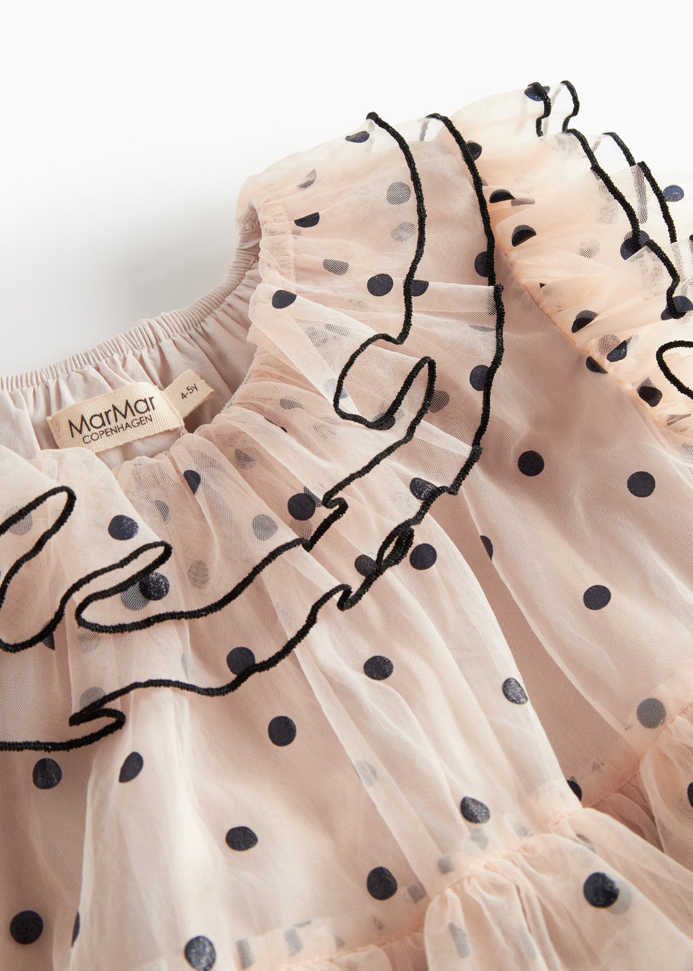 Nærbillede af krave med sorte flæser og prikker på lys beige julekjole i tyl til børn