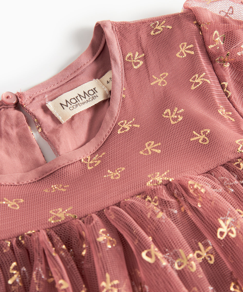 Nærbillede af overdel på rosa festkjole til børn i tyl med små gyldne mønstre