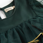 Nærbillede af mørkegrøn julekjole for børn i tyl med guldkanter og flæser