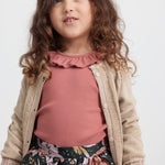 Pige iført mørkegrøn nederdel med blomsterprint, rosa bluse og beige cardigan til børn