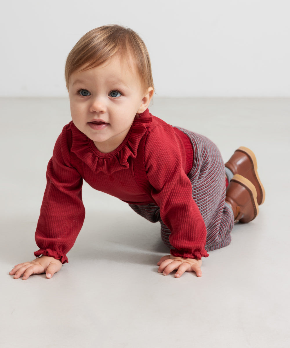 Baby i rød ribbet body med flæsekrave og strikkede bukser