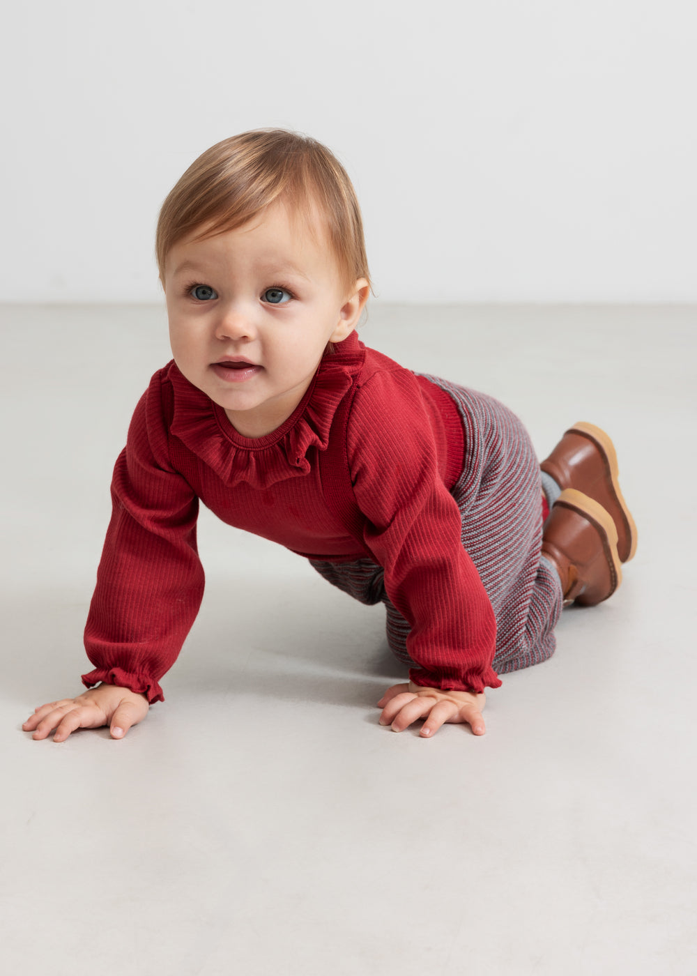 Baby i rød ribbet body med flæsekrave og strikkede bukser