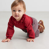 Baby iført strikkede bukser med røde og grå striber og rød juletrøje