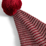 Strikket nissehue med røde og grå striber og kvast til børn