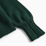 Ärme på mørkegrøn strikket cardigan med hulmønster og ribkanter til baby