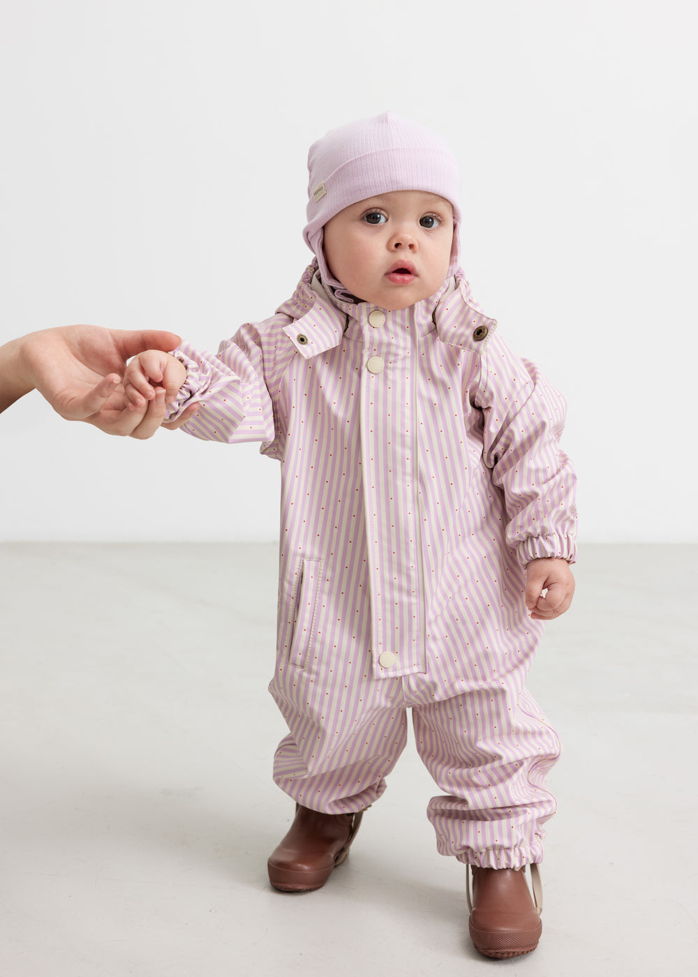 aby iført lyserød stribet regndragt med hætte og matchende hue