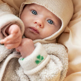 Baby i beige fleecejakke og beige strikket hue set tæt på