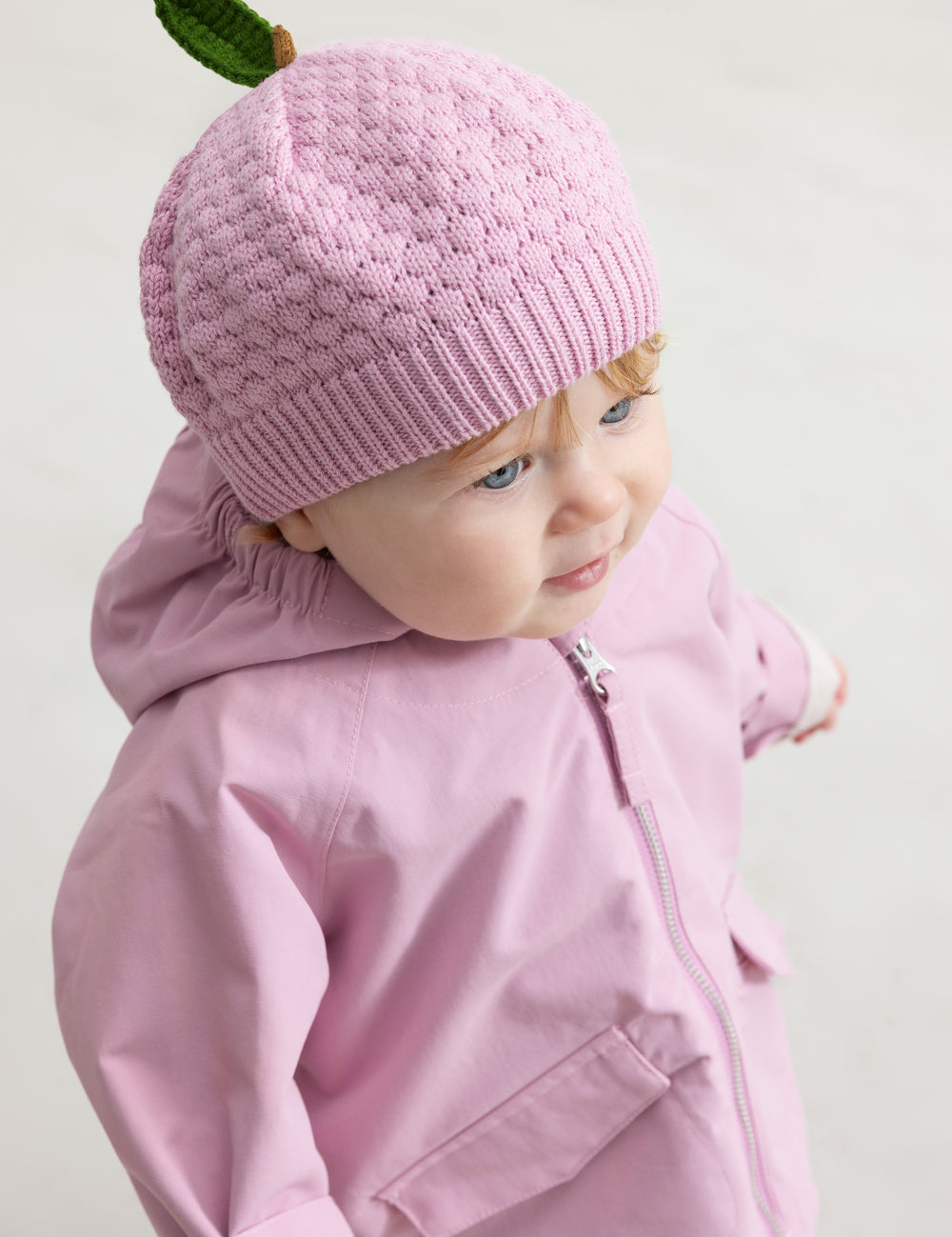 Baby i lyserød strikket hue og rosa jakke