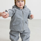 Baby iført grå overgangsjakke og grå overtræksbukser