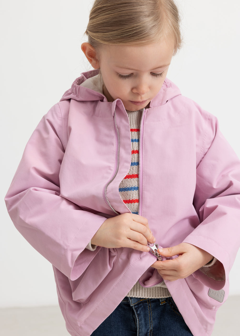 Barn iført lyserød overgangsjakke med hætte og knapper