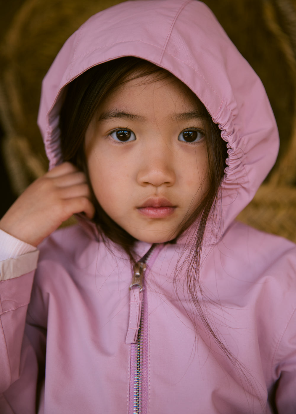Barn i lyserød overgangsjakke med hætte tæt på ansigtet