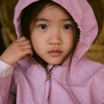 Barn i lyserød overgangsjakke med hætte tæt på ansigtet